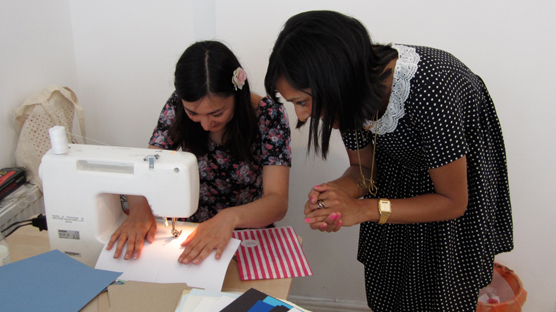 Using the sewing machine to stitch together notebooks.