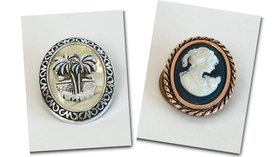 A pair of scarf clips featuring a palm tree and a cameo.